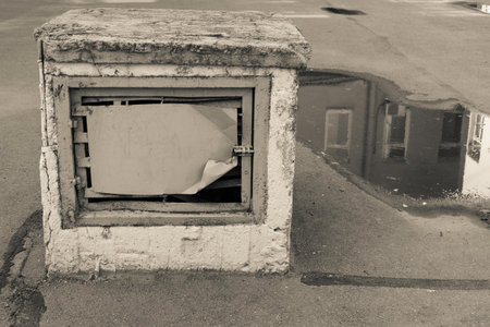 old construction for ventilation in the yard against a puddle with reflection of a fragment of the...