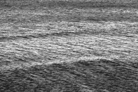 the big textured water surface with ripples for an abstract natural background of dark gray or black colorの写真素材