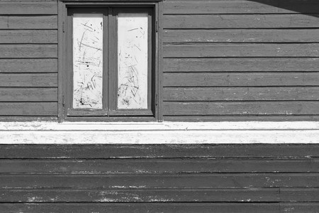 fragment of an old wall of the house from wooden boards with one big window monochrome gray toneの写真素材