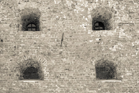 windows in niches on an old brick wall of ancient fortress or prison