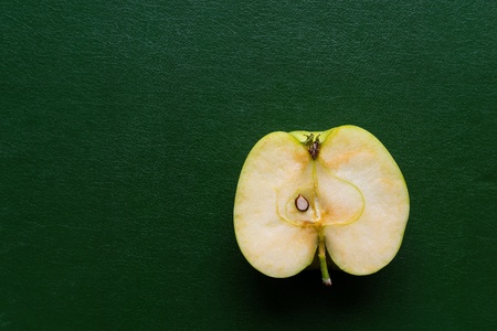 longitudinal cut or section of one apple as the isolated object closeup on green or against a dark backgroundの写真素材