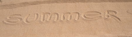 the word summer is written by a closeup on the sandy surface of the beach or coastの写真素材
