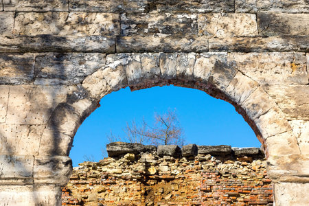 ancient ruins of a stone arch and the destroyed brick wallの写真素材