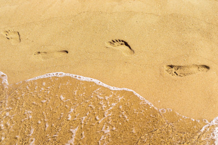 traces of human legs and water on the sandy surface of the beach or coastの写真素材