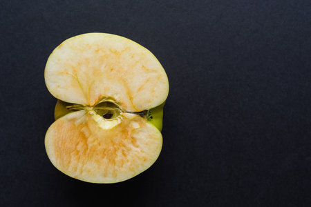 longitudinal cut or section of one apple as the isolated object closeup on black or against a dark...