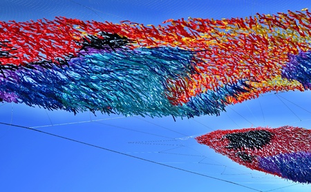 festive abstract tinsel closeup from color tapes of fabric or from textile material against the background of the blue skyの写真素材