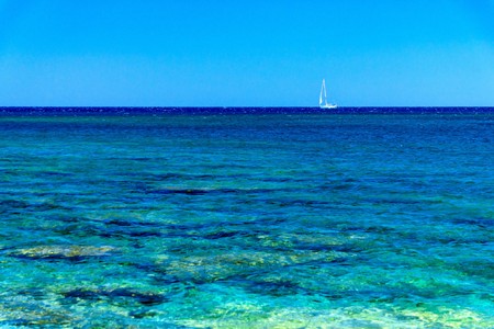 sea landscape with the small sailing yacht in a distance on the horizonの写真素材