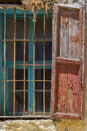 very old window with an iron lattice and with a wooden sun blindの写真素材