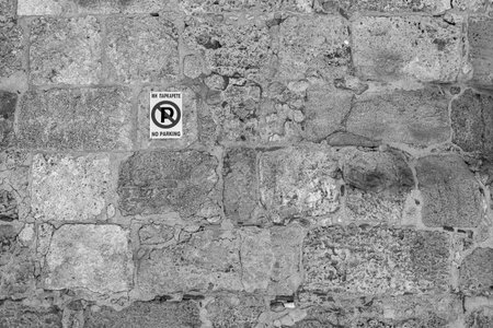 one street sign the parking of motor transport is forbidden on an old stone wall of monochrome toneの写真素材