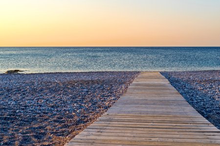 morning sea landscape of the empty beach with a path from a wooden flooring closeup and sharpness on a backgroundの写真素材