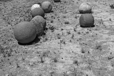 ancient stone spheres or kernels are located chaotically and abstractly on the old dry soil of monochrome toneの写真素材