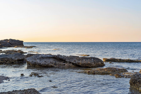 wild morning landscape of the stony sandy coast closeup and the line of the horizon over water