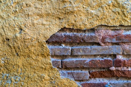 the combined texture of the old peeled plaster on a surface of a brick wall closeupの写真素材