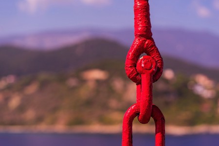 links of an old lifting sling of red color closeup on an indistinct natural background in retro styleの写真素材