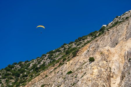 one sports parachute a hang-glider soars in the blue sky over the stone hill or the rockの写真素材