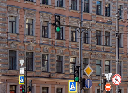 old city and different street signs and traffic lights against the background of a wall of the old European building with a set of windowsの写真素材