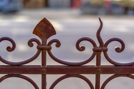 part of an old metal fencing closeup on an indistinct street backgroundの写真素材