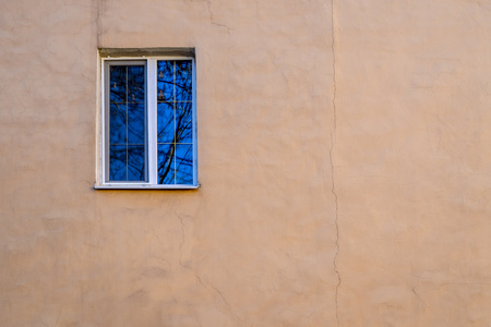 one window on the empty and big old plastered wall for a backgroundの写真素材