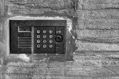 one panel of the old on-door speakerphone on an old concrete wall a closeup of black-and-white toneの写真素材