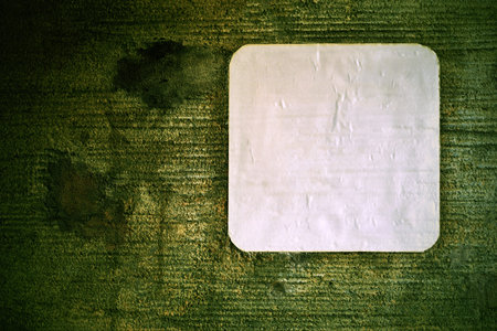 one empty swhite leaf of paper or clean sticker closeup on an old concrete wall for a background...
