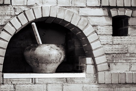brick facade of the old rural furnace for cooking and a pig-iron pot or a saucepan for food closeup of monochrome toneの写真素材