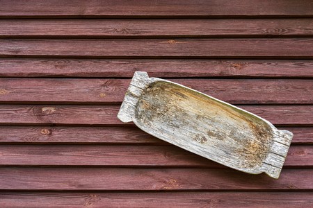 one old wooden trough for washing or a feeding trough closeup hangs on a wooden board wallの写真素材