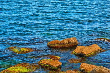 sea stones in the water and over the water in the foreground and the background of the sea with ripplesの写真素材