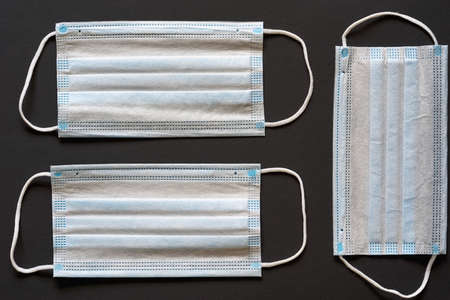 three individual disposable medical masks for antibacterial and antimicrobial respiratory protection are located close-up on a dark background and empty space for textの写真素材