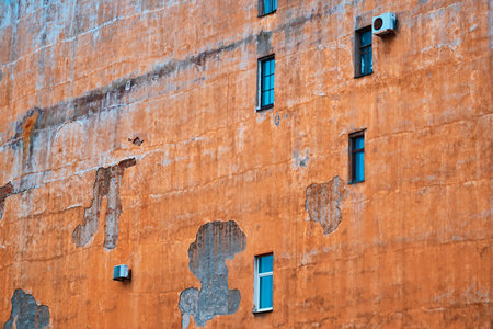 part of the large plastered wall of an old house with small windows and plenty of empty space for a vintage backgroundの写真素材
