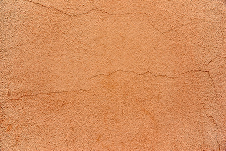 old plastered wall surface with thin cracks for rough textured background or orange pale wallpaperの写真素材