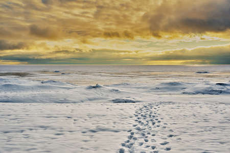 morning or evening landscape of a large icy lake and cloudy sky for a natural background with a horizon lineの写真素材