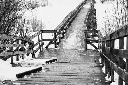 abstract empty old wooden bridge closeup and with snow in winter or spring on a black and white photo of a monochrome toneの写真素材