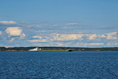 river landscape with a floating barge against the background of a blue sky with white cloudsの写真素材
