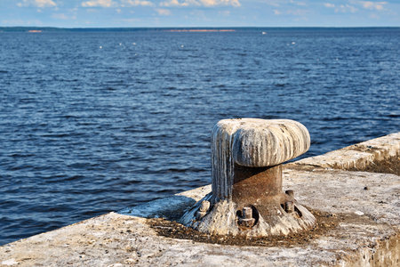 one old iron bollard closeup on the shore on a concrete plate for mooring the vessel