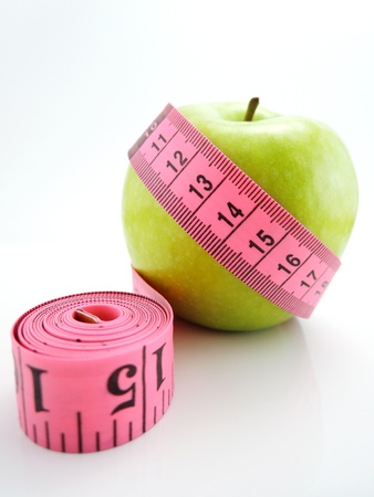 Green apple with pink measuring tape isolatedの写真素材
