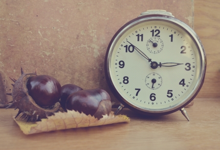 Vintage chestnut and clock on wooden backgroundの写真素材