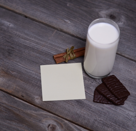 Glass of milk with cinnamon and chocolate with blank paper の写真素材