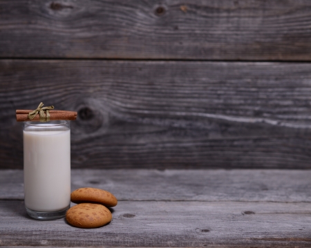 Glass of milk with cinnamon and gingerbread on wooden backgroundの写真素材