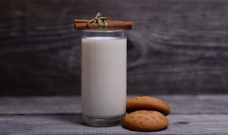 Glass of milk with cinnamon and gingerbread on woodenの写真素材