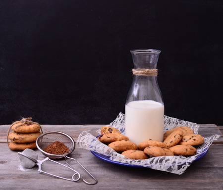 Bottle of milk with cookies and some ingredients on rustic tableの写真素材