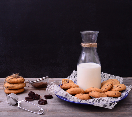 Bottle of milk with cookies and some ingredients on rustic tableの写真素材