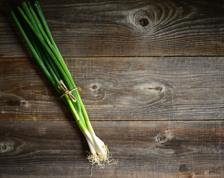 Bunch of spring onions on woodの写真素材