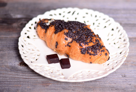 Chocolate croissant on white plate on tableの写真素材