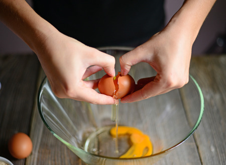 Close-up picture of hands broking eggs.の写真素材
