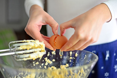 Closeup of a pair of hands cracking an egg into a glass bowlの写真素材