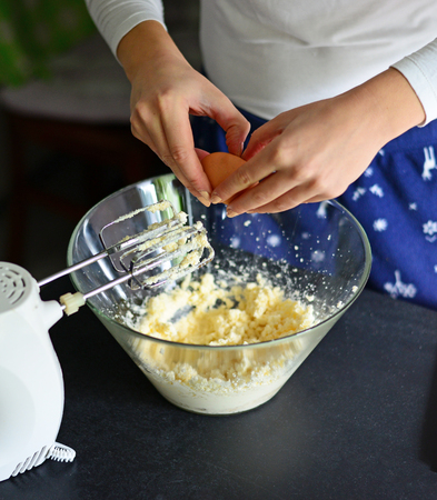 Closeup of a pair of hands cracking an egg into a glass bowlの写真素材