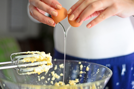 Closeup of a pair of hands cracking an egg into a glass bowlの写真素材