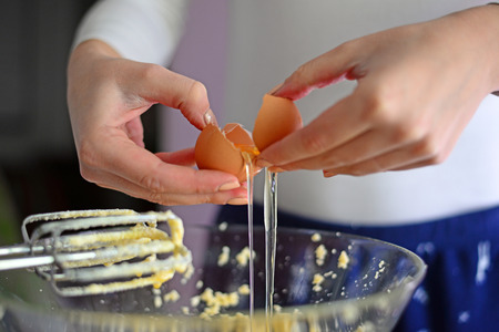 Closeup of a pair of hands cracking an egg into a glass bowlの写真素材