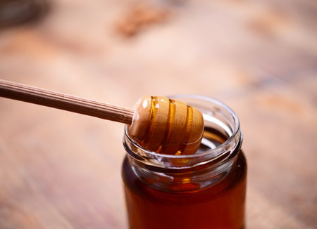 Honey drip in jar on the tableの写真素材