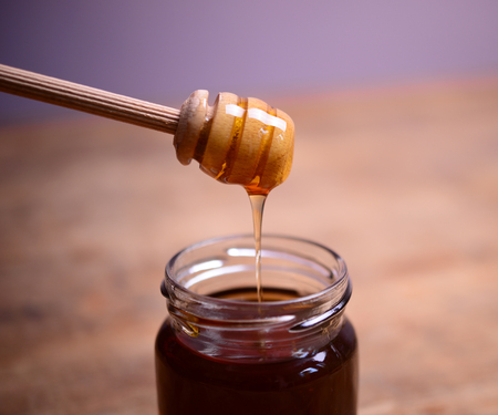 Honey drip in jar on the tableの写真素材